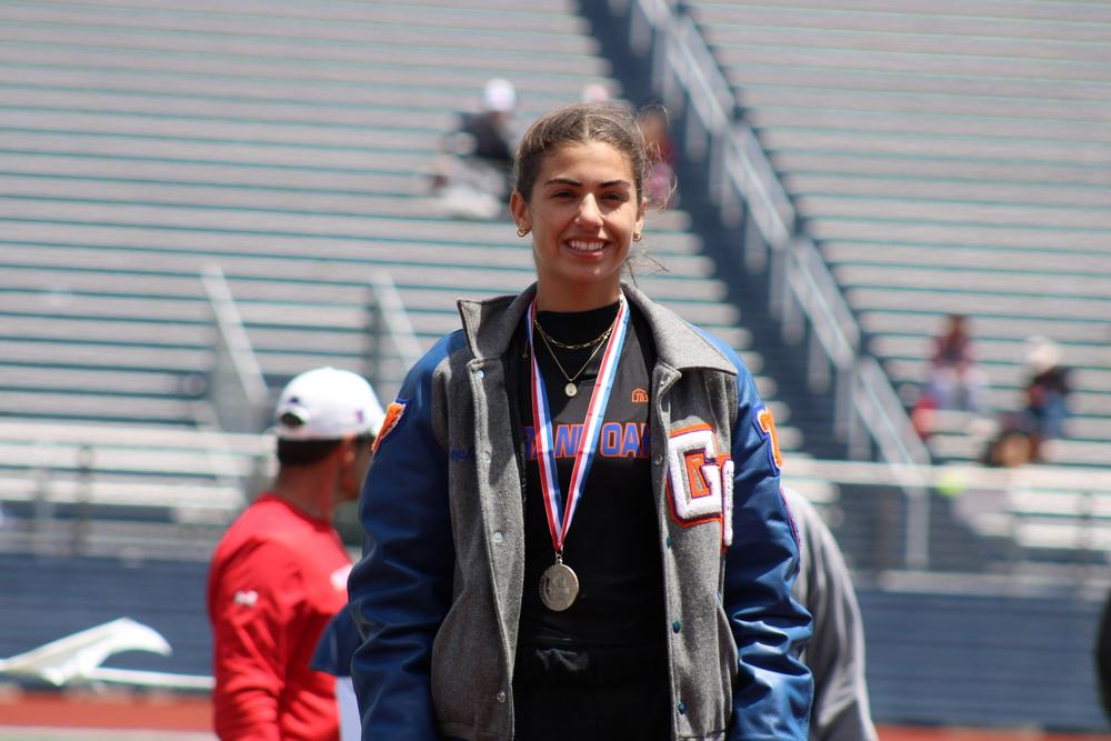 Sophia Kowalski wearing a medal and her Grand Oaks letter jacket at a high school meet